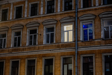 one lit window in rows of dark windows on the facade of a building