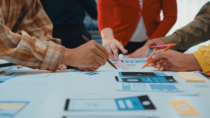 A diverse team gathers around a table filled with colorful sketches and tools, engaged in user interface design. The atmosphere is collaborative and innovative. SACTR