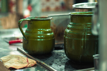 Two green metal pots with a vintage design placed on a stovetop, with visible stains and steam marks, in a rustic kitchen setting.