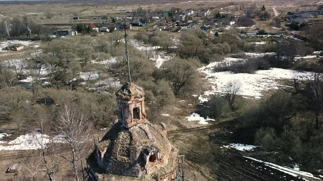 An old brick church on the background of a village in early spring