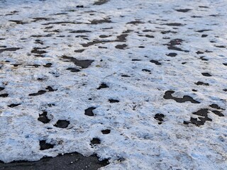The process of melting snow on urban pavement presents a fascinating blend of nature and city life. A captivating view of partially melted snow is revealing the underlying pavement