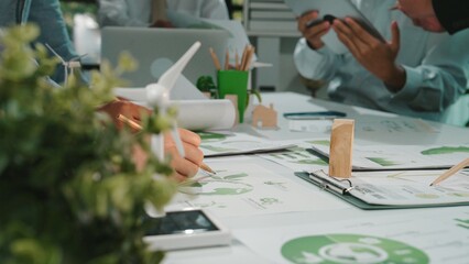 Engaging teamwork in a modern workspace focused on sustainability and innovative design solutions. Professionals discuss eco-friendly strategies amidst creative materials. SACTR