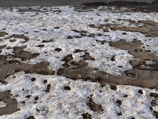 The process of melting snow on urban pavement presents a fascinating blend of nature and city life. A captivating view of partially melted snow is revealing the underlying pavement