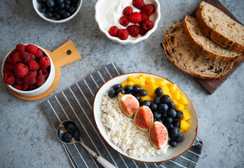 Cottage cheese with berries for breakfast. A plate of cottage cheese with mango, figs and blueberries	
