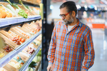 Positive elderly man buying seasonal vegetables in local market