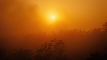 Sunset glimpse through hazy orange sky over distant silhouettes of trees at dusk