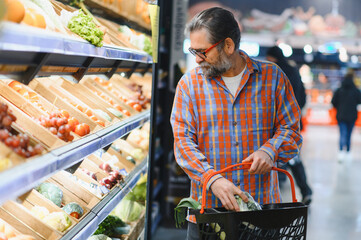Positive elderly man buying seasonal vegetables in local market