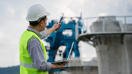 Construction worker in a safety vest is standing next to a large blue crane
