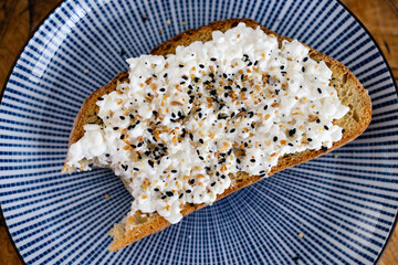 slice of sourdough toast on a blue ceramic plate topped with cottage cheese and everything bagel spice