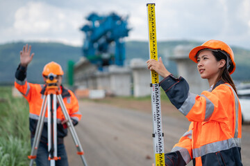 Survey team is working with a theodolite and road construction plans. Civil engineers are taking...