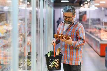 Male shopper chooses chicken eggs in a grocery supermarket