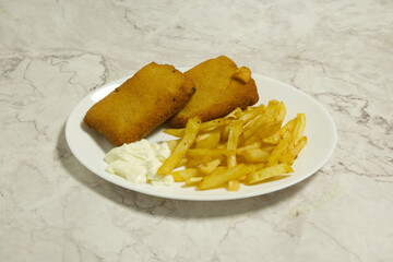 A plate of fried fish and fries sits on a marble countertop
