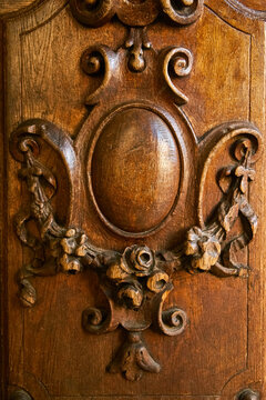 Close-up of carved wooden decor on the front door with intricate patterns. A detail of an antique furniture or architectural element. Warm brown tones, wood grain and skillful carving 