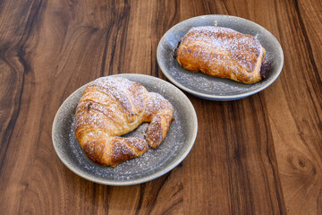 Two plates of croissants with powdered sugar on top