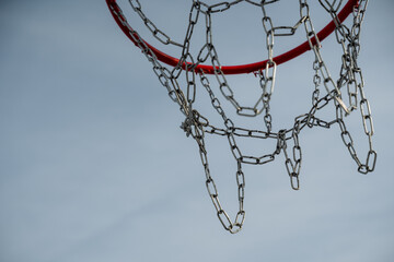 This detailed closeup image of a basketball hoop, featuring a shiny chain net contrasted against a...
