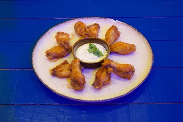 A plate of chicken wings with a dipping sauce