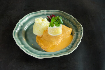 A plate of food with a piece of meat and a lemon wedge on top