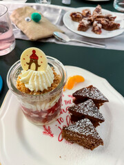 Dessert im Gläschen mit Sahne, Beerenmousse und Hafercrunch, auf einem Teller mit Gewürzkuchen in Tannenbaum Form serviert
