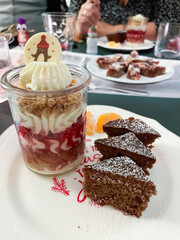 Dessert im Gläschen mit Sahne, Beerenmousse und Hafercrunch, auf einem Teller mit Gewürzkuchen in Tannenbaum Form serviert