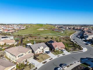 This aerial photo of Park Ridge in Antioch, California, showcases modern homes, Julpun Park, winding streets, and yellow wildflower fields, blending suburban life with nature under a clear blue sky.