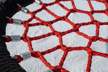 A striking closeup view of a vibrant, colorful rope net structure, prominently featured against a...