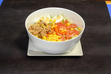 A bowl of salad with carrots, tomatoes, and eggs