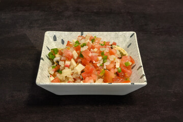 A bowl of food with tomatoes and peppers