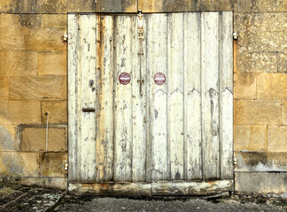 Old building facade featuring wooden door, with stone walls.For the background of your photos and collages
