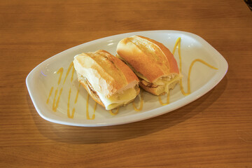 Two sandwiches on a white plate with a yellow sauce