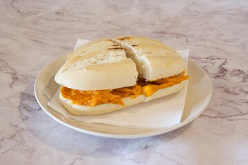 A sandwich with a slice missing is on a white plate