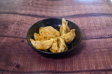 A bowl of dumplings sits on a wooden table