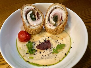 Crispy stuffed meat rolls with creamy mashed potatoes, roasted cherry tomato, and fresh greens. A gourmet dish with rich flavors, perfect for restaurant menus and fine dining photography.