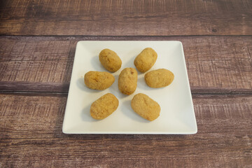 A plate of fried doughnuts with a wooden table underneath