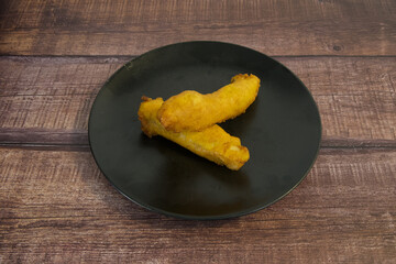 Two pieces of fried food on a black plate