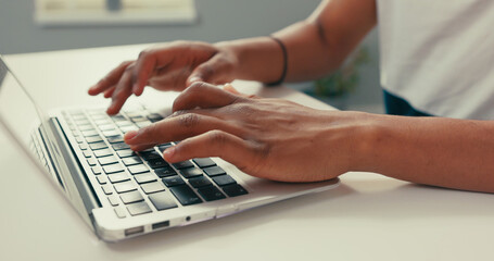 Close-up of silver latop standing on white desk, dark-skinned man working on it, young hands,...