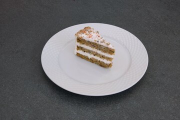 A slice of carrot cake sits on a white plate