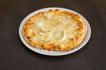 A pizza with cheese and toppings sits on a white plate
