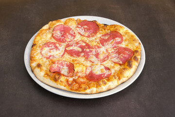 A pizza with pepperoni on it is sitting on a white plate