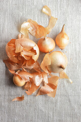 Onions peels with whole vegetable from above overhead top view on textile texture background, flat lay, zero waste and sustainable living concept