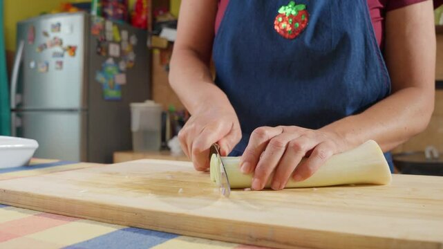 Woman chopping leek on wooden cutting board