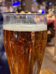 One tall glass filled with refreshing golden lager beer, bubbling delightfully on a rustic wooden surface. Refreshing Cold Beer Served in Pint Glasses Resting on a Rustic Wooden Table Surface