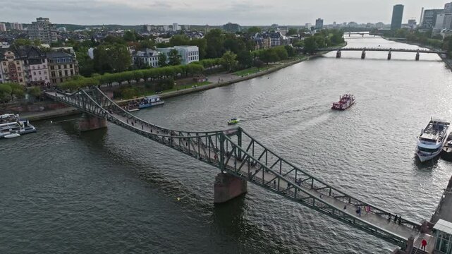 Aerial Drone View of the Iron Footbridge (Eiserner Steg) in Frankfurt, Germany &ndash; Historic Pedestrian Bridge Spanning the Main River, Offering Scenic Views of the City Skyline, Waterfront, and Cultural