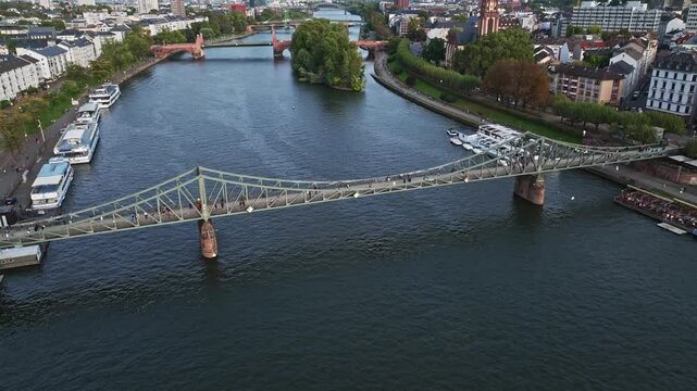 Aerial Drone View of the Iron Footbridge (Eiserner Steg) in Frankfurt, Germany &ndash; Historic Pedestrian Bridge Spanning the Main River, Offering Scenic Views of the City Skyline, Waterfront, and Cultural
