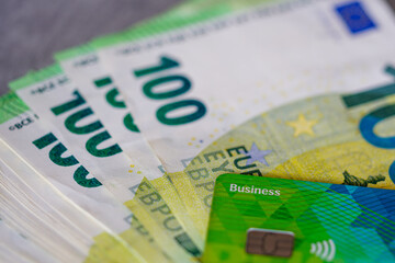 Green business payment card placed on 100 euro banknotes, credit card and cash concept