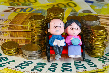A symbol of financially secure retirement, an elderly couple of doll figurines sitting on a bench