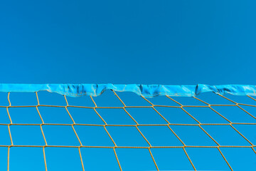 Close up shot of volleyball net, blue sky, view from below