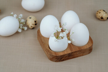 White eggs with flowers on wooden tray. Easter background. Farm concept.
