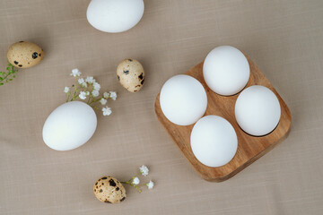White eggs and quail eggs on wooden tray