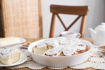 Delicious frosted cinnamon rolls on wooden table indoors, closeup