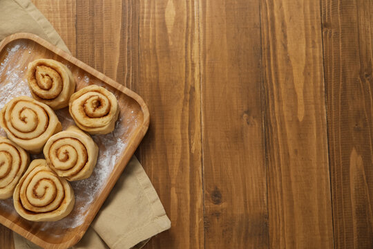 Raw cinnamon rolls on wooden table, top view. Space for text